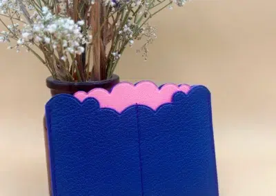 Porte-cartes bleu et rose devant des fleurs séchées